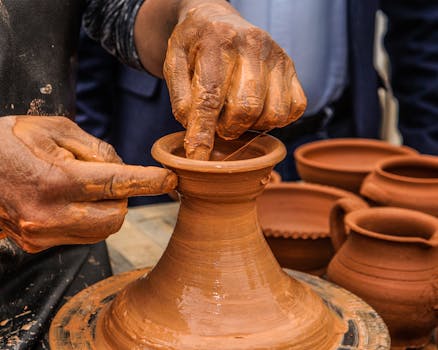 Hands meticulously shaping a clay pot on a pottery wheel, highlighting traditional craftsmanship.